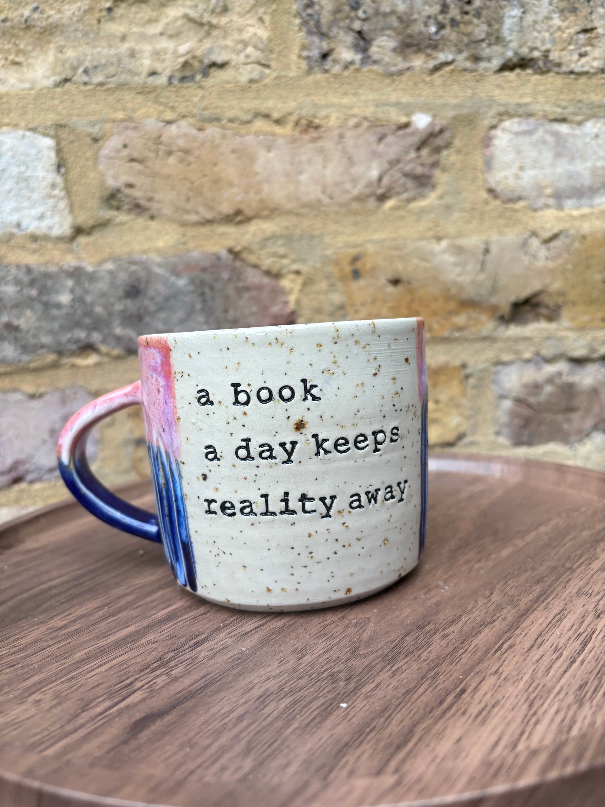 Large “A book a day keeps reality away" mug (pink sky)