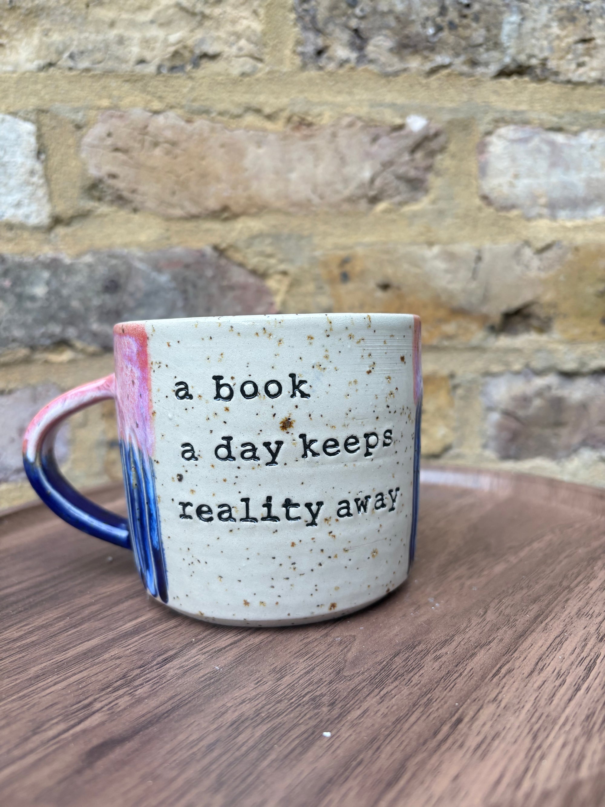 Large “A book a day keeps reality away" mug (pink sky)